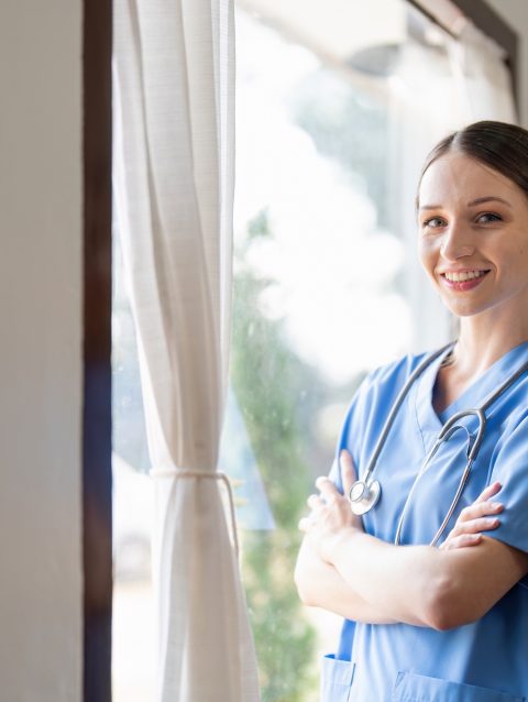 Portrait of a friendly female doctor or nurse wearing blue scrubs uniform and stethoscope, with